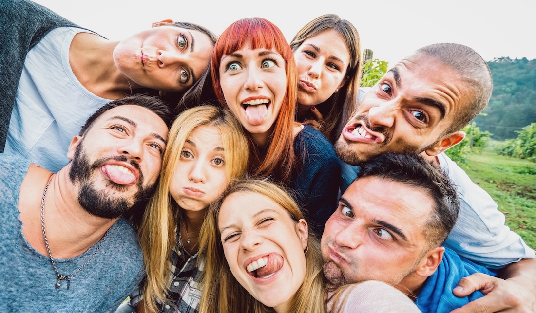 Best friends taking funny selfie at picnic excursion sticking out tongue - Youth life style concept with young people having fun together outdoors - Warm bright filter with focus on central faces