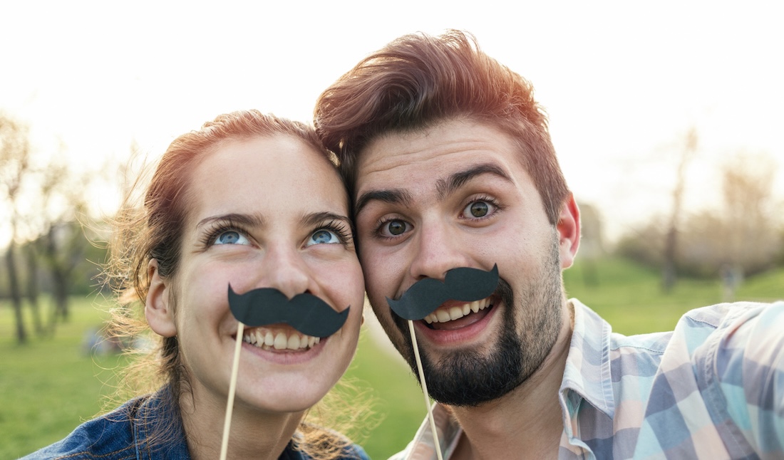Couple having good time, making selfie with fake mustaches