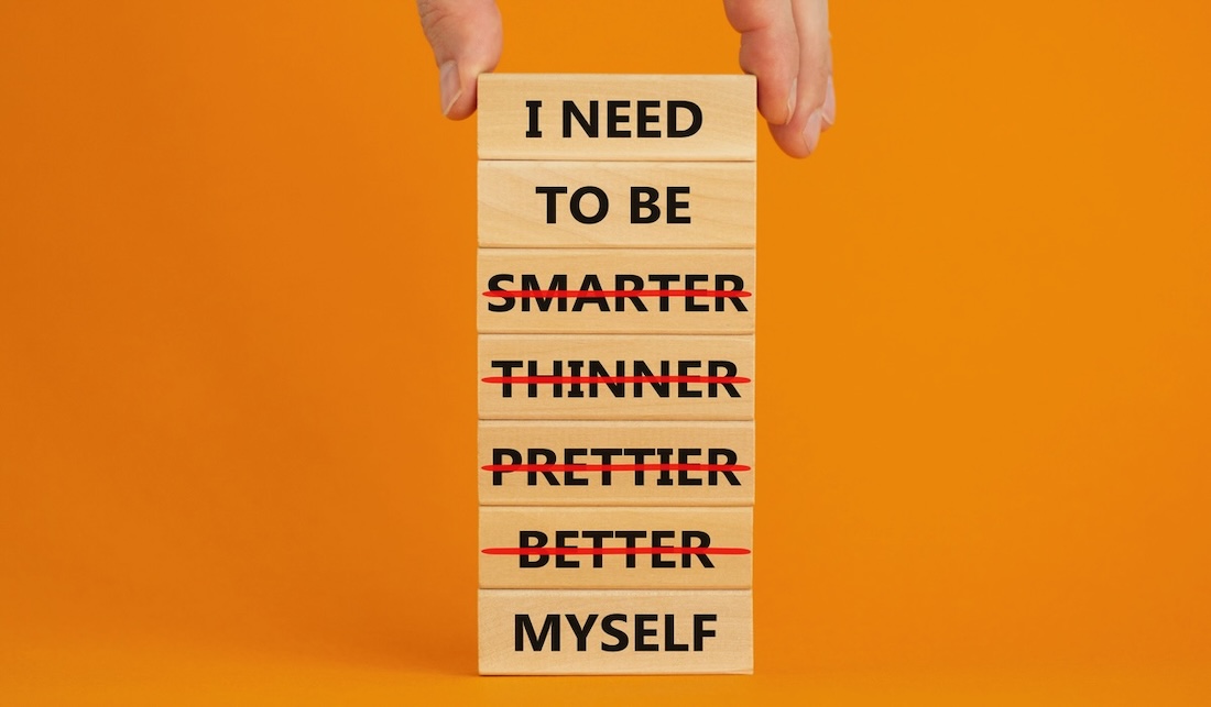 Be myself symbol. Businessman hand. Wooden blocks with words 'i need to be myself, not smarter, thinner, prettier, better'. Beautiful orange background, copy space. Psychological, be myself concept.